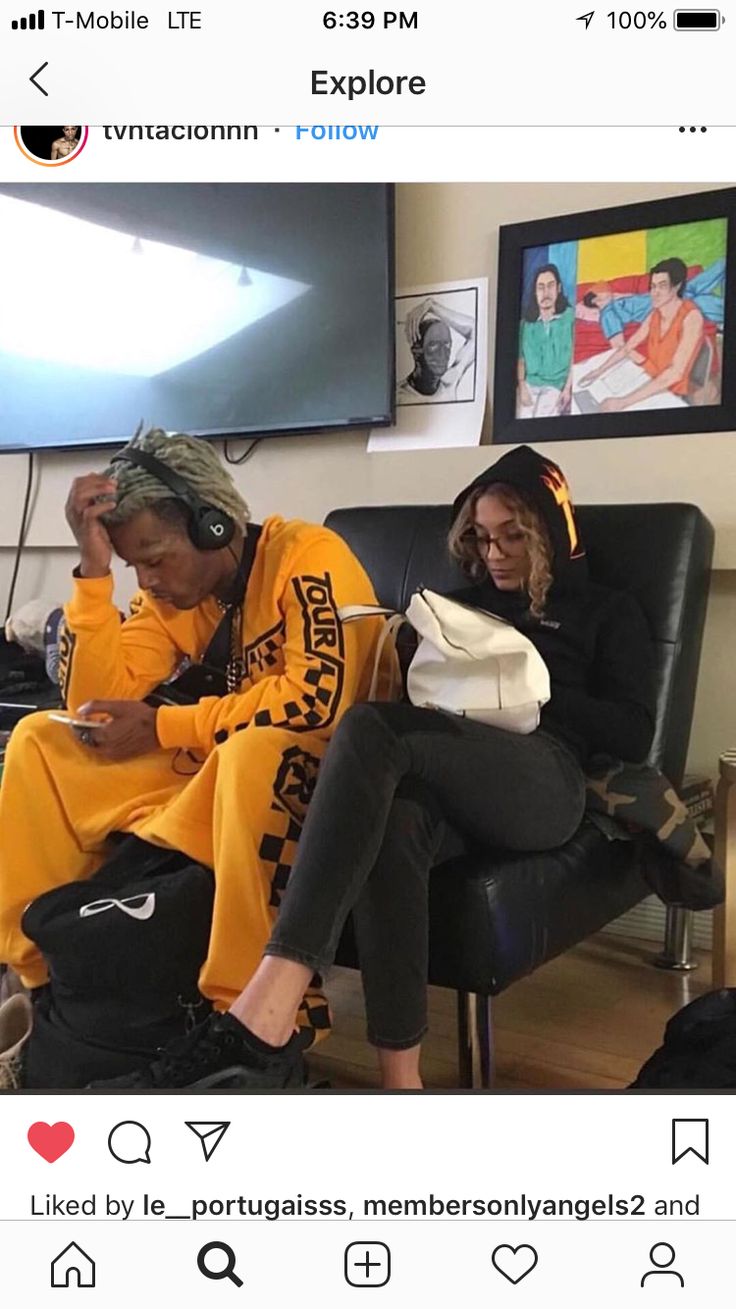 two people sitting on a couch in front of a flat screen tv and wearing matching sweatshirts