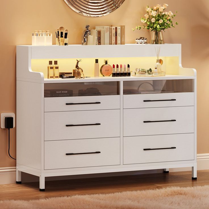 a white dresser with drawers and lights on it