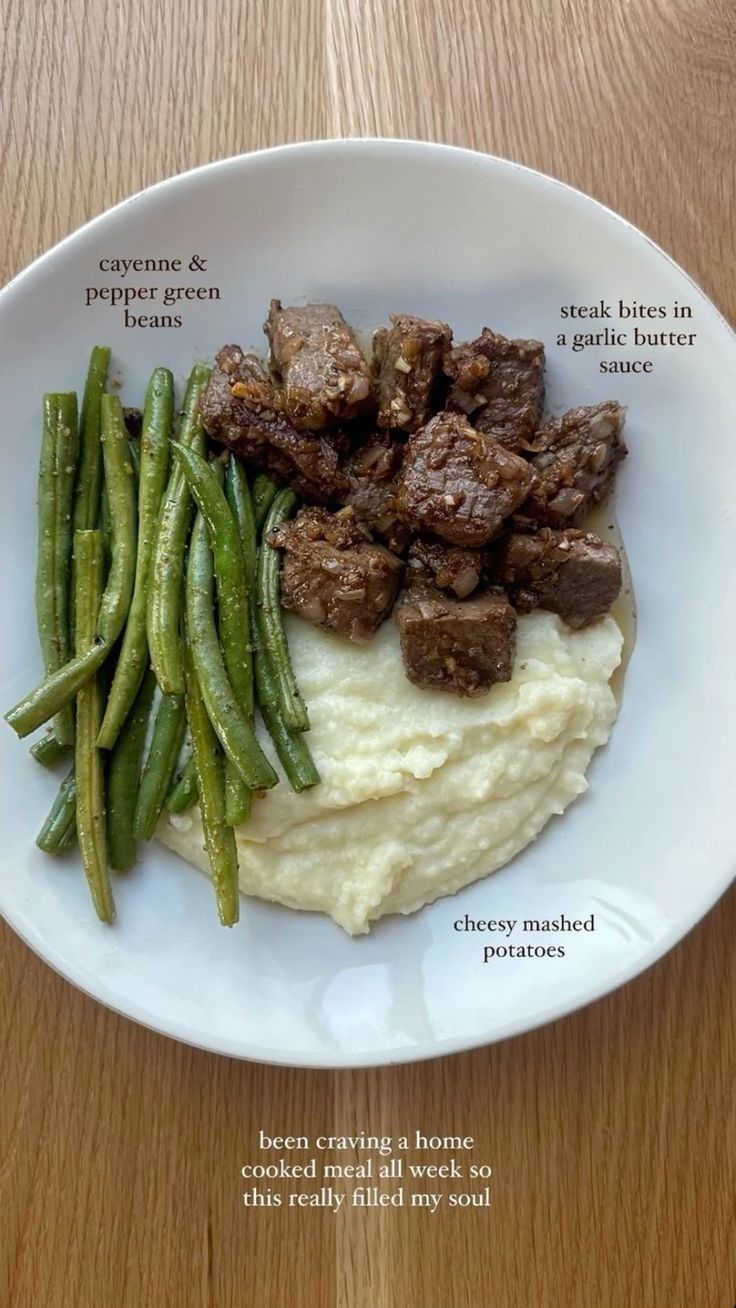 a white plate topped with mashed potatoes and green beans next to meat on top of mashed potatoes