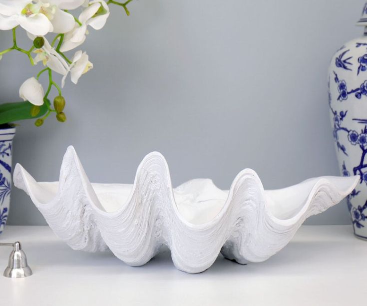 a white vase sitting on top of a table next to a blue and white vase