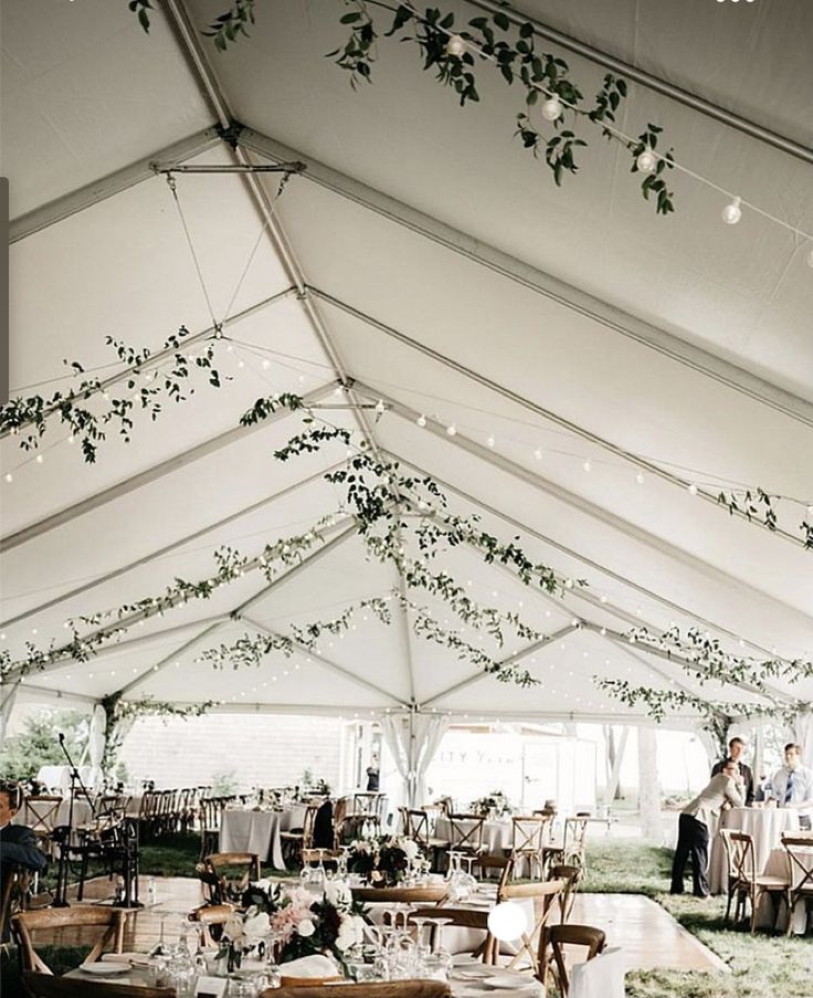 the inside of a tent with tables and chairs set up for an outdoor wedding reception