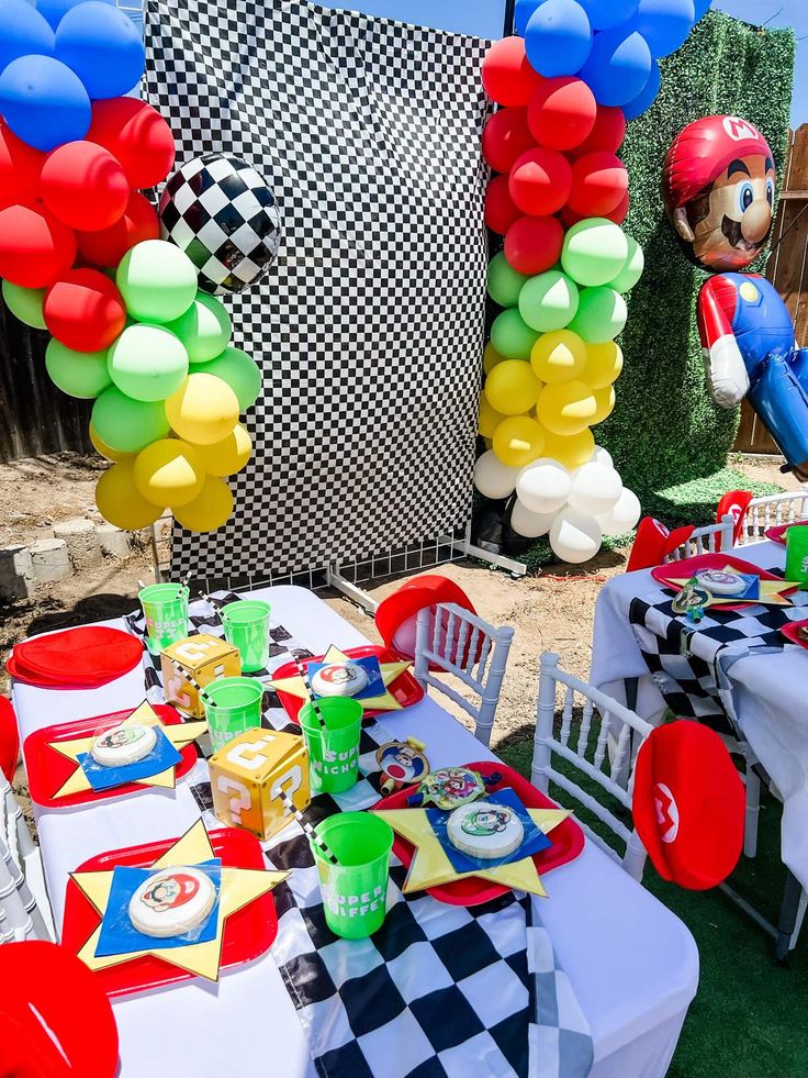 mickey mouse balloon decorations and table set up for a birthday party with checkered table cloths