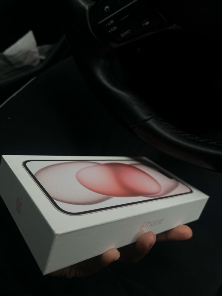 a person holding an apple product in their hand, with the box still attached to it