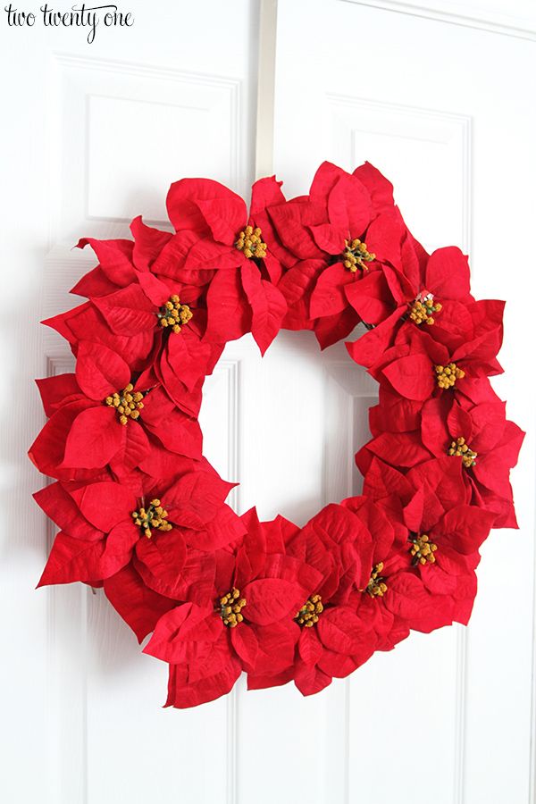 a red poinsetti wreath hanging on a white door