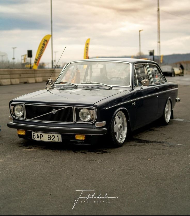 an old black car parked in a parking lot