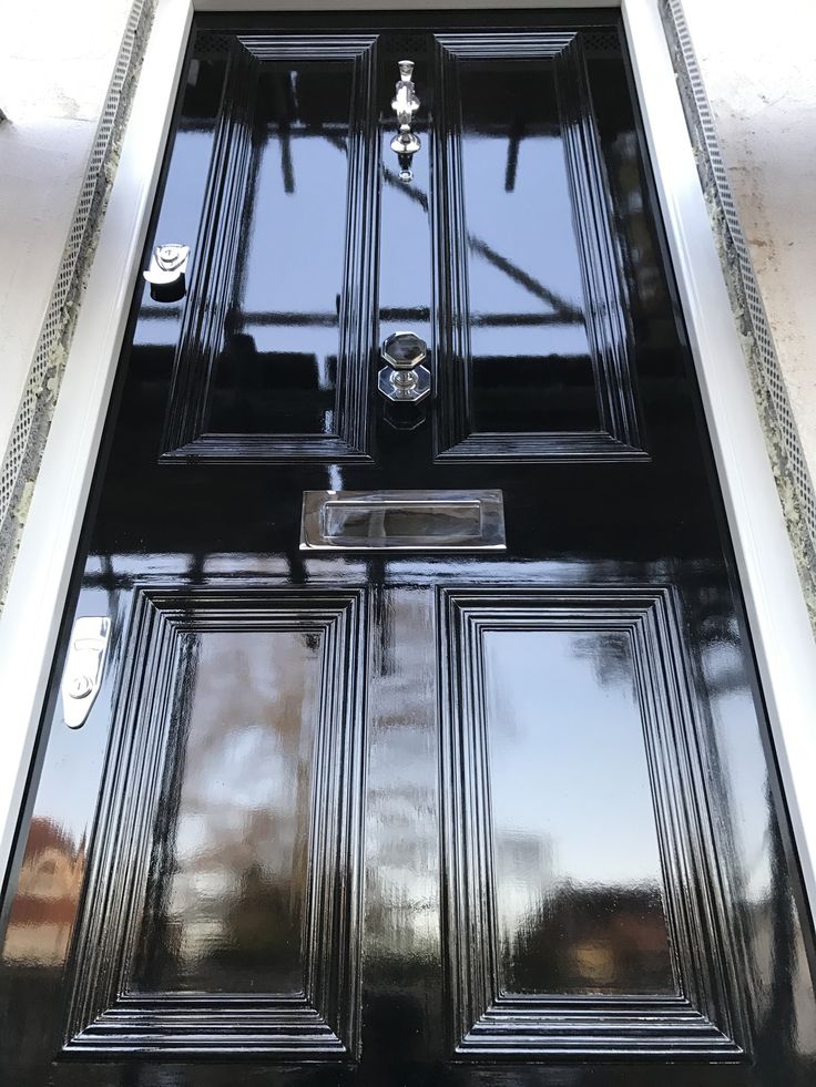 the front door is black and has two glass panels on each side, along with a metal handle