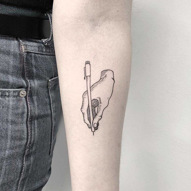 a hand holding a pen tattoo on the arm