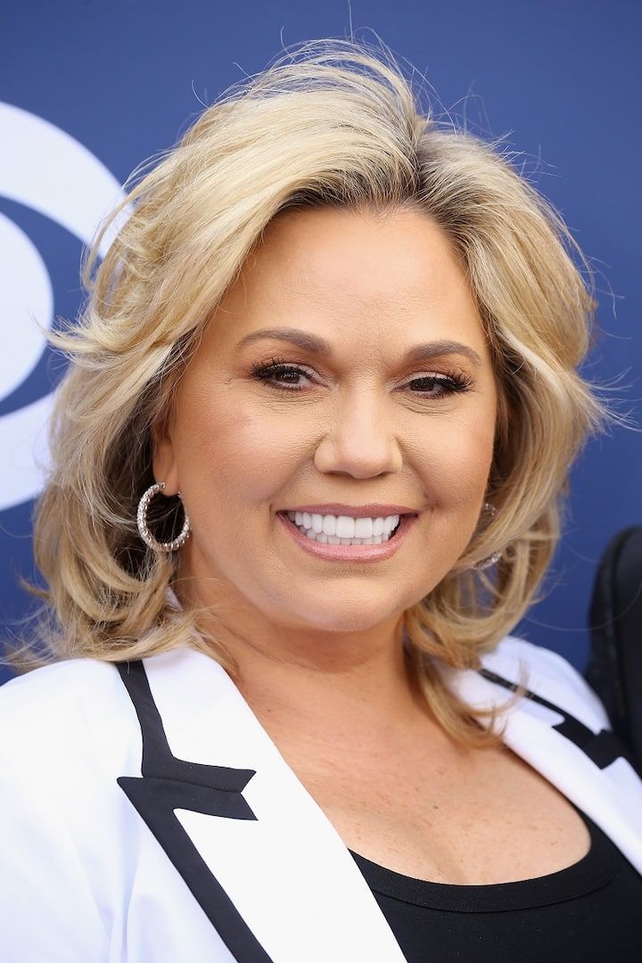 a woman with blonde hair and earrings smiling at the camera