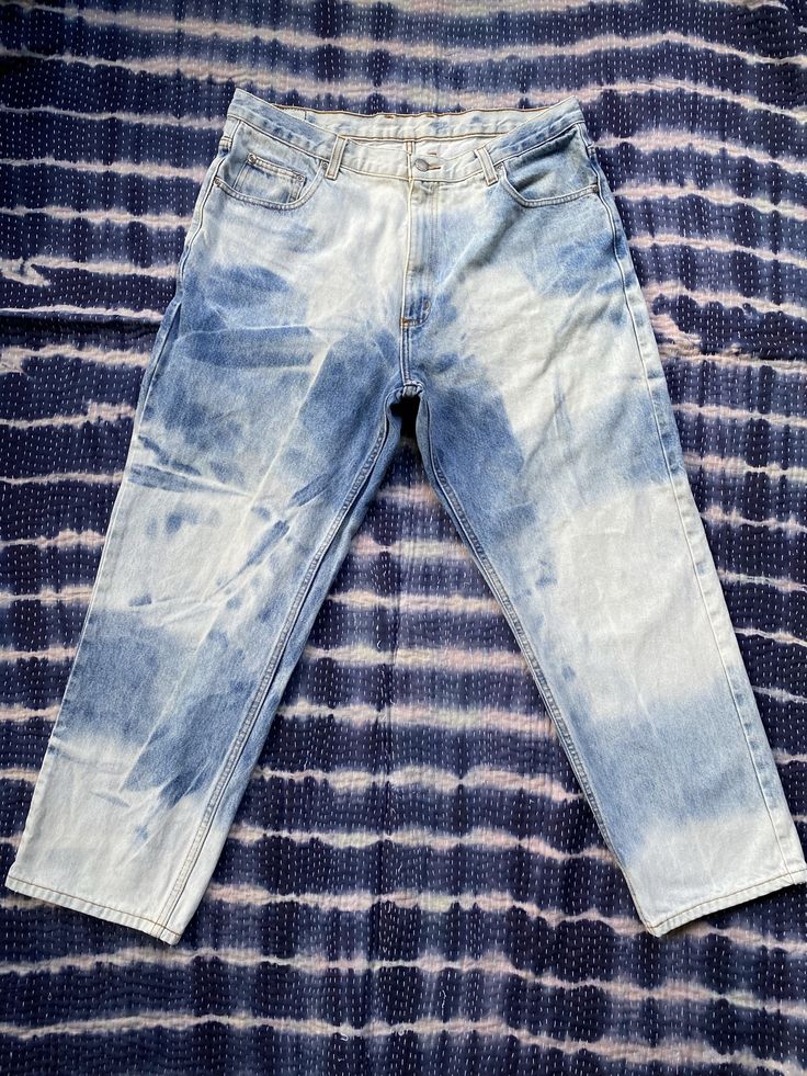 a pair of blue jeans sitting on top of a purple and white tie - dyed cloth