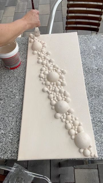 a person is painting rocks on a white piece of art that looks like an arrow