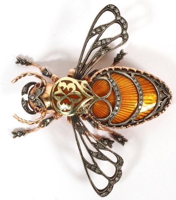 a brooch with an orange and yellow bee on it's back end, surrounded by silver filigreets