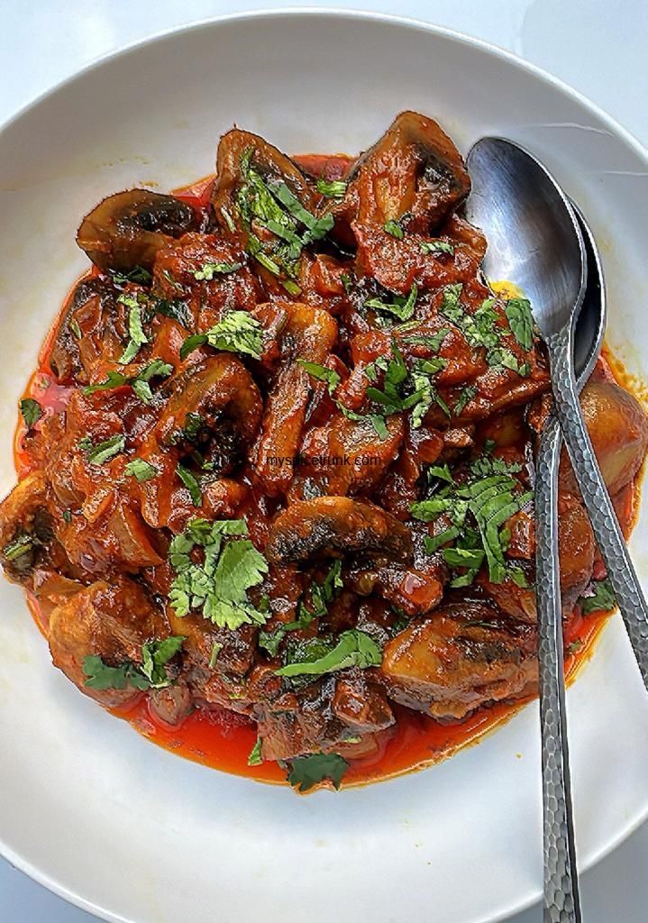 a white plate topped with meat covered in sauce and garnished with parsley