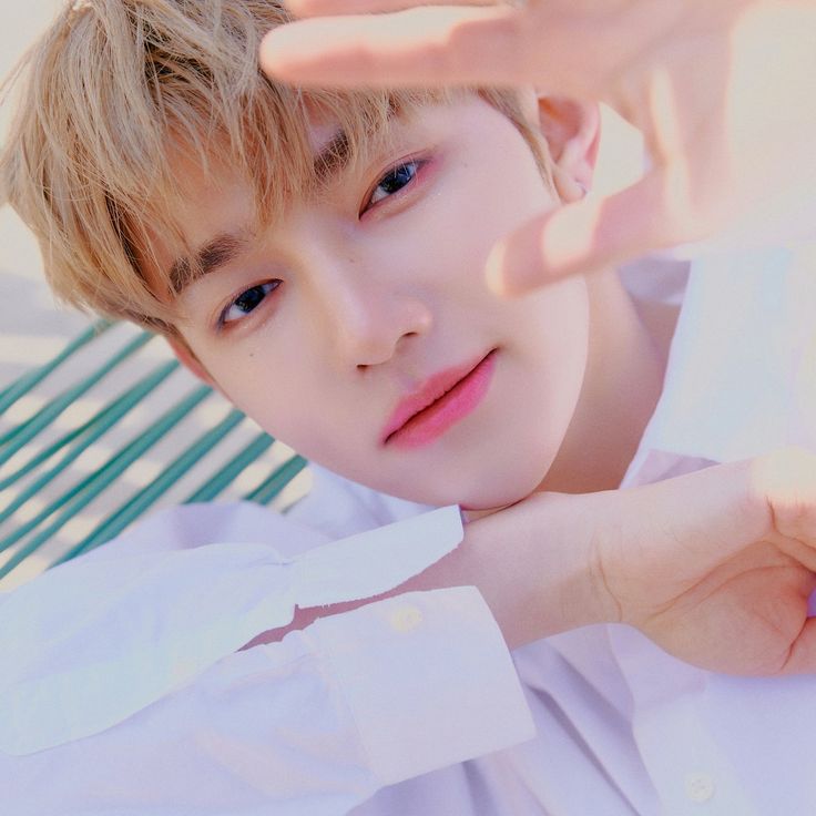 a young man is posing for the camera with his hand on his head and wearing a white shirt