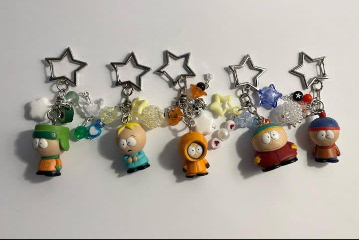 several key chains with cartoon characters hanging from them on a white surface in the shape of stars