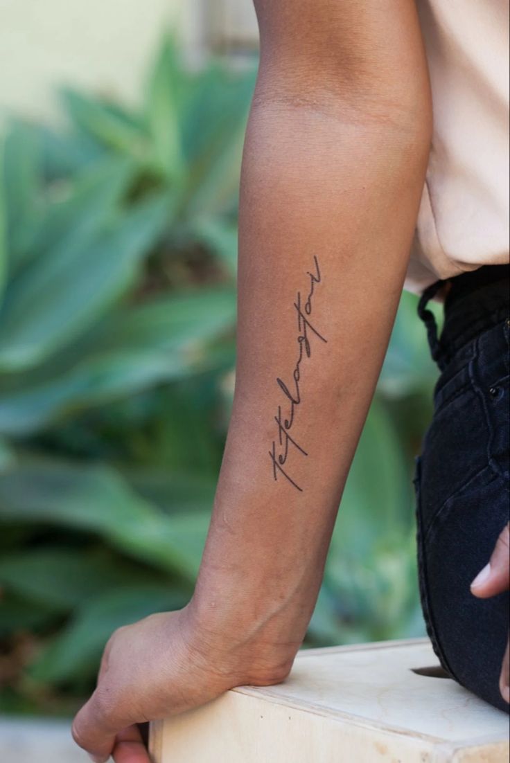 a woman with a tattoo on her arm holding onto a stool and looking down at the ground