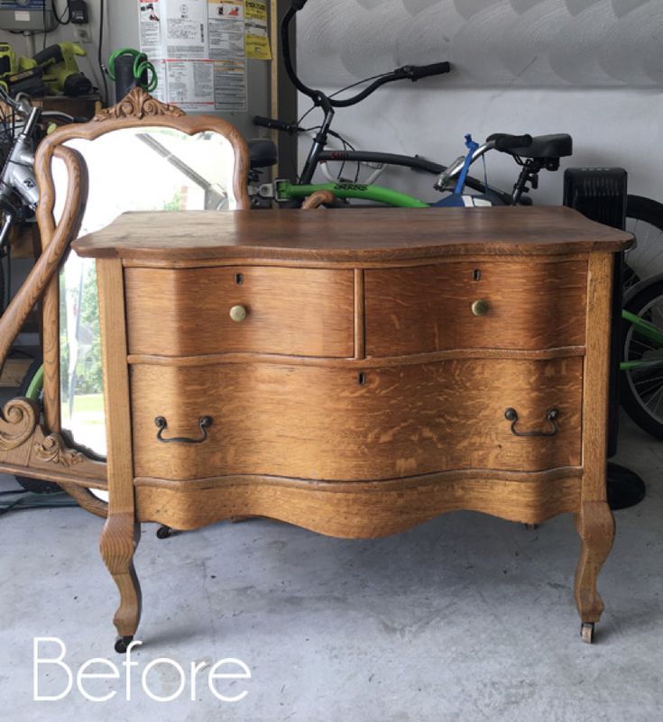 an old dresser with a mirror on top and bicycles in the back ground behind it