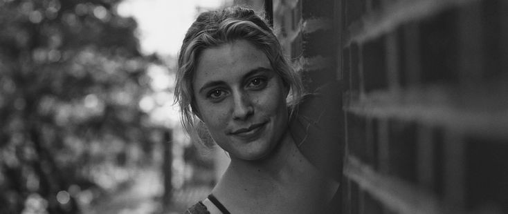 a black and white photo of a woman leaning against a wall