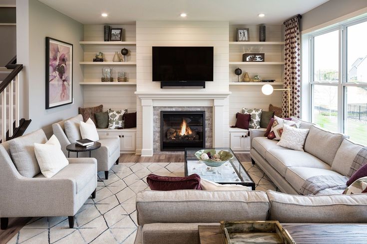 a living room filled with furniture and a flat screen tv mounted on the wall above a fire place