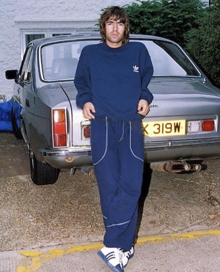 a man standing in front of a car with his hands on his hips and looking at the camera