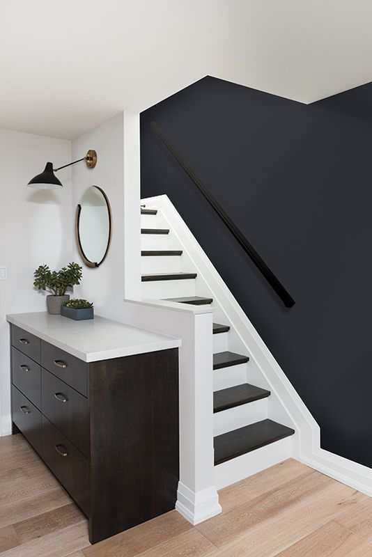 a black and white stair case next to a table with a potted plant on it