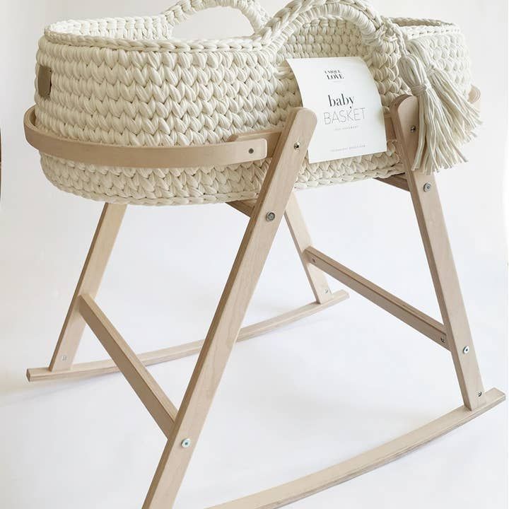 a baby's cradle with a label on it and a wooden stand holding a basket