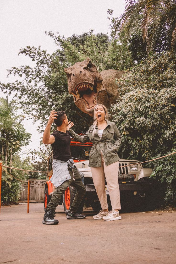 two people standing in front of a fake t - rexe and another person taking a photo