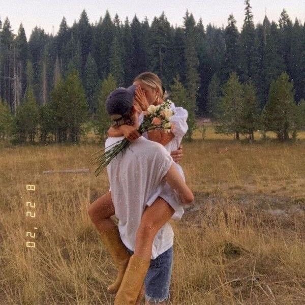 two people are hugging in the middle of a field