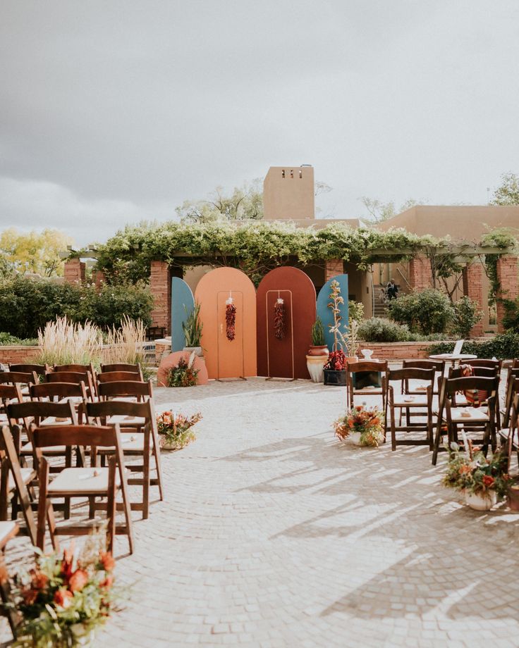 an outdoor ceremony setup with wooden chairs and flowers