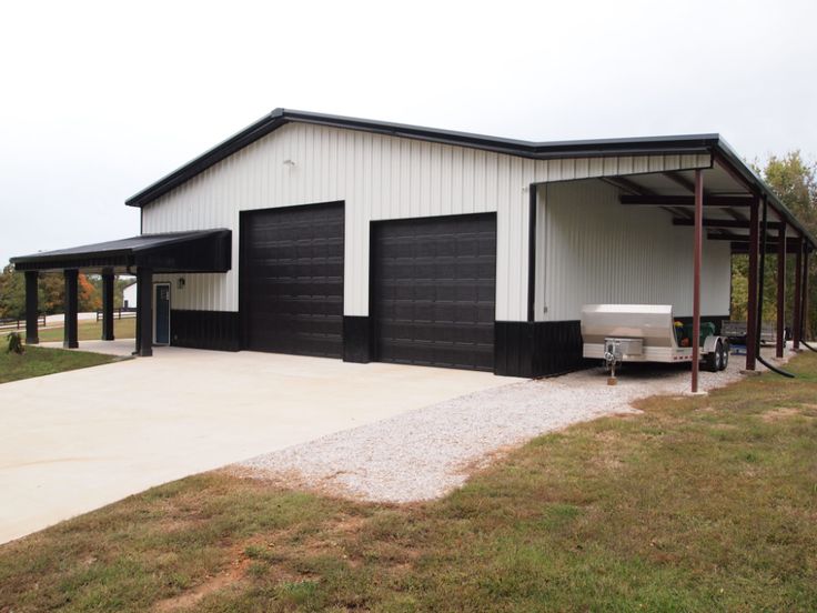 a two car garage with an attached carport in the middle of a grassy area