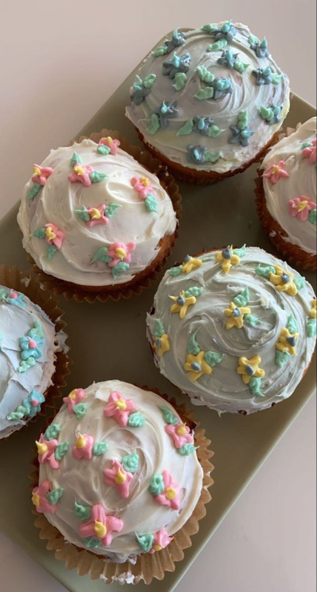 six cupcakes with frosting and sprinkles on them sitting on a plate