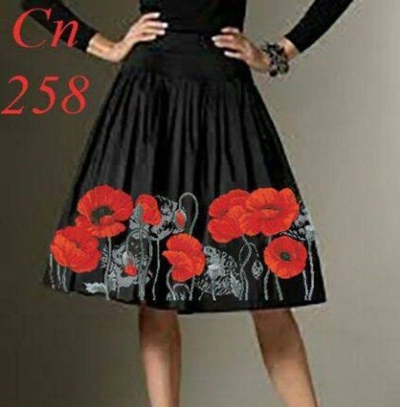 a woman wearing a black dress with red flowers on it