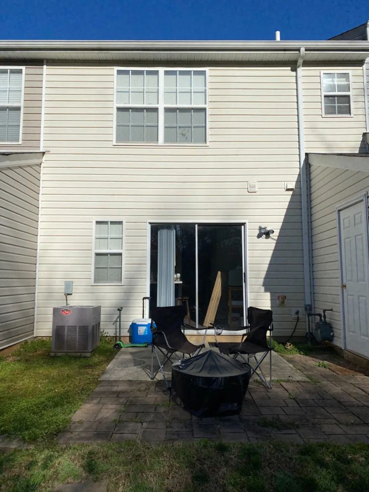 an outside view of a two story house with patio furniture and fire pit in the yard