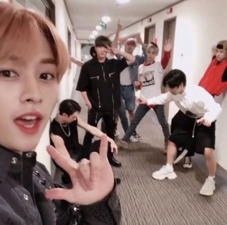 a group of young men standing next to each other in a hallway with one person making the peace sign