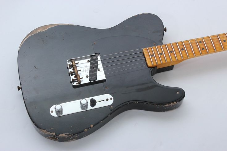 an old black electric guitar sitting on top of a table