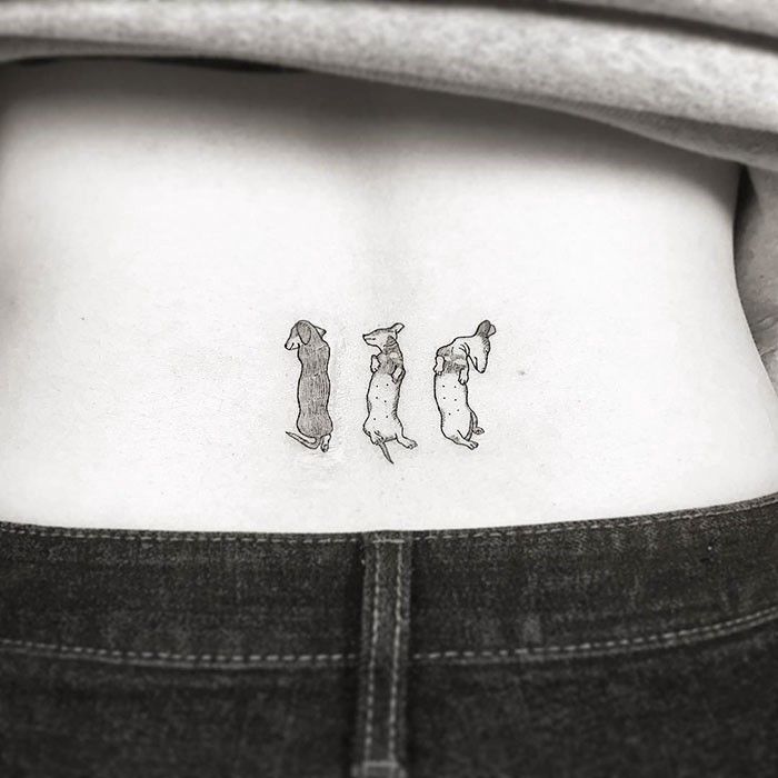 a woman's lower back tattoo with three dogs on her left side ribcage