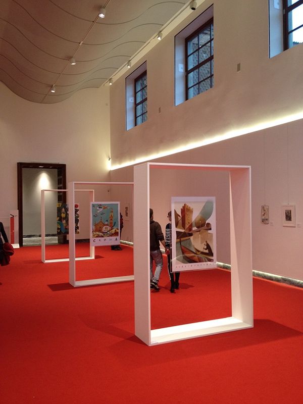 people are standing in an art gallery with red carpet and white columns on the floor