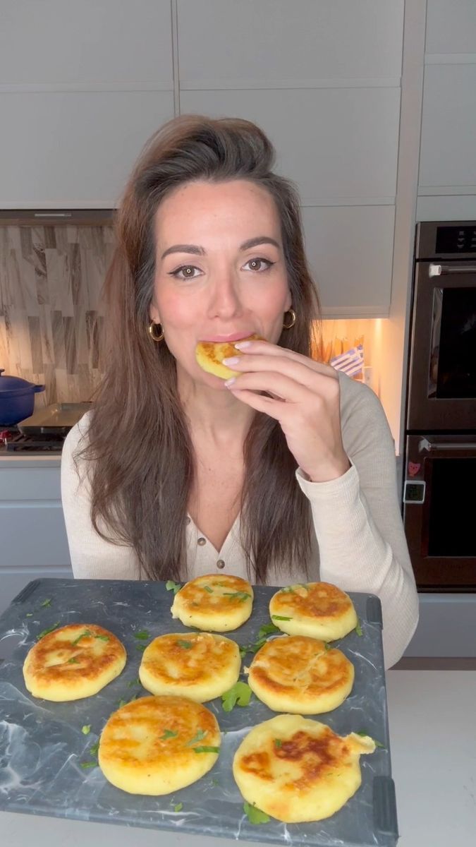 a woman is taking a bite out of some food on a tray in the kitchen