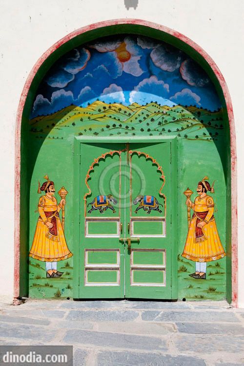 an ornate green door with paintings on it