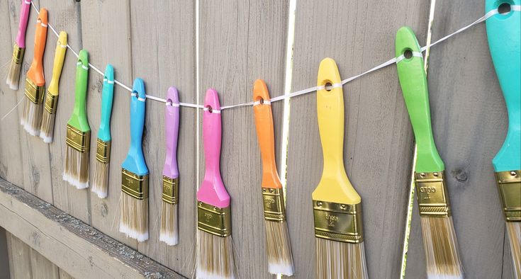 colorful paintbrushes are hanging on a clothesline with toothbrushes attached to them