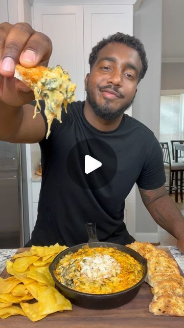 a man holding up a slice of pizza in front of his plate with tortilla chips