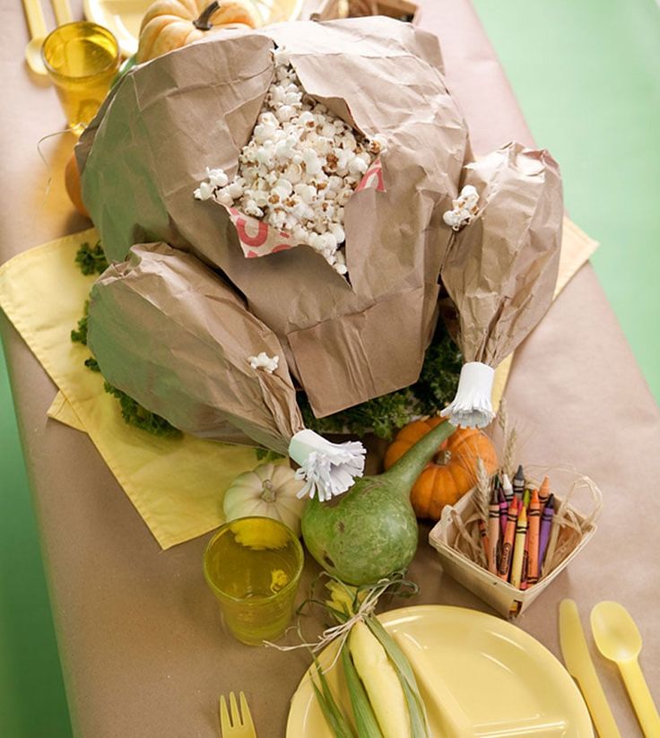 the table is set with yellow plates and silverware, wrapped in brown paper bags