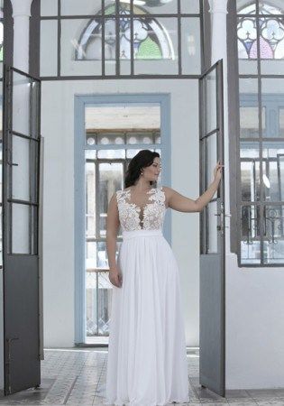 a woman in a white dress is walking through an open doorway with her hand on the door handle