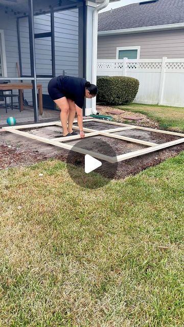 a woman is bending over to put concrete in the ground with her hands and feet