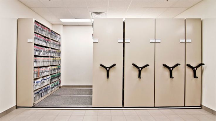 an empty room with three white lockers and several black hooks on the wall next to each other