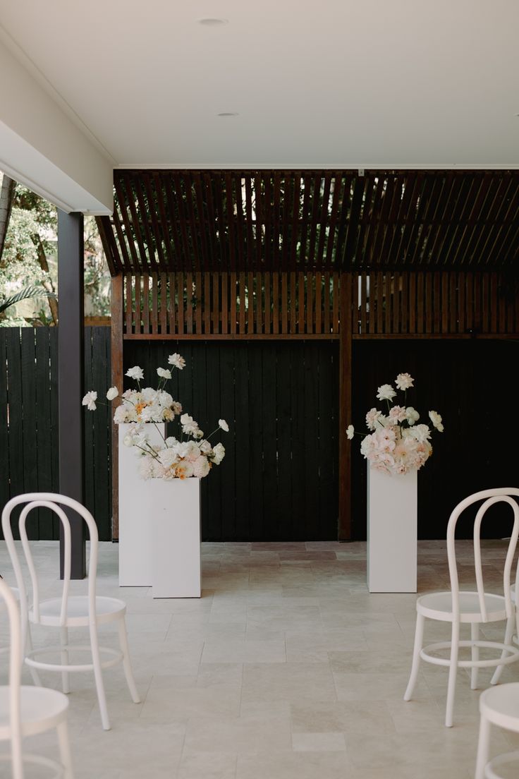 two white vases filled with flowers sitting on top of chairs next to each other