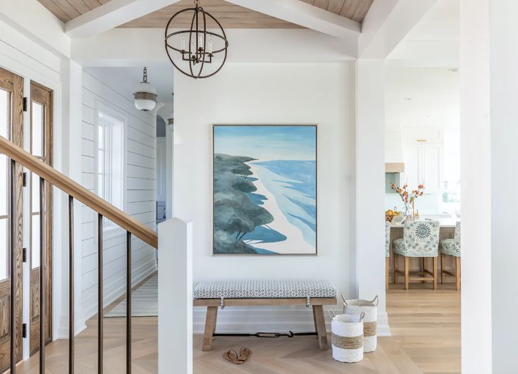 a painting hanging on the wall above a bench in a room with wooden floors and white walls