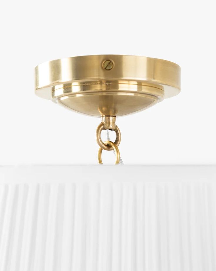 a close up of a light fixture on a white surface with a gold ring hanging from it's center