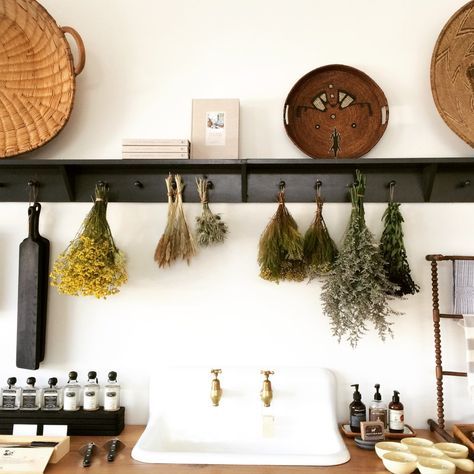 the kitchen counter is covered with spices and herbs hanging from hooks on it's wall