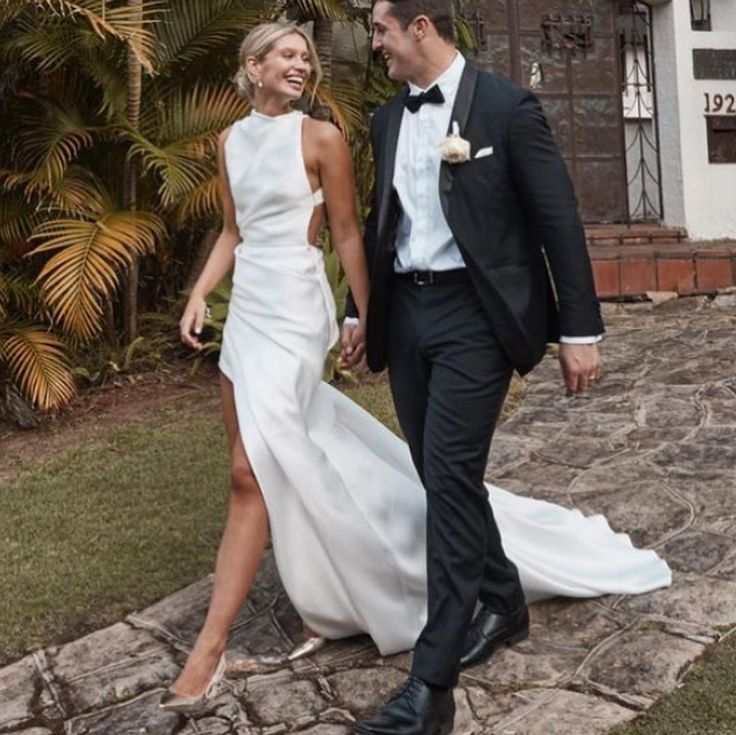 a man and woman in formal wear walking down a stone path holding each other's hand