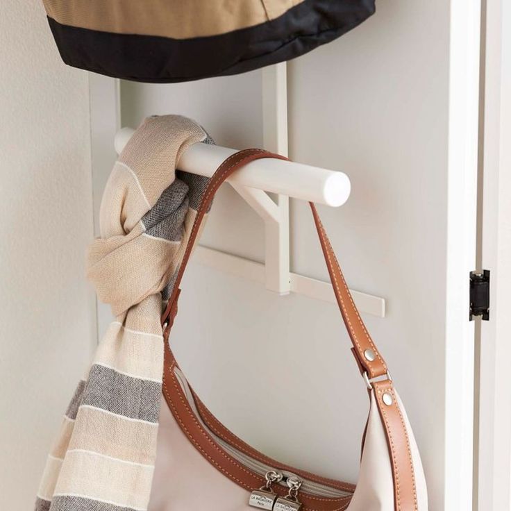 a purse hanging on a coat rack next to a hat and scarf hang from the wall